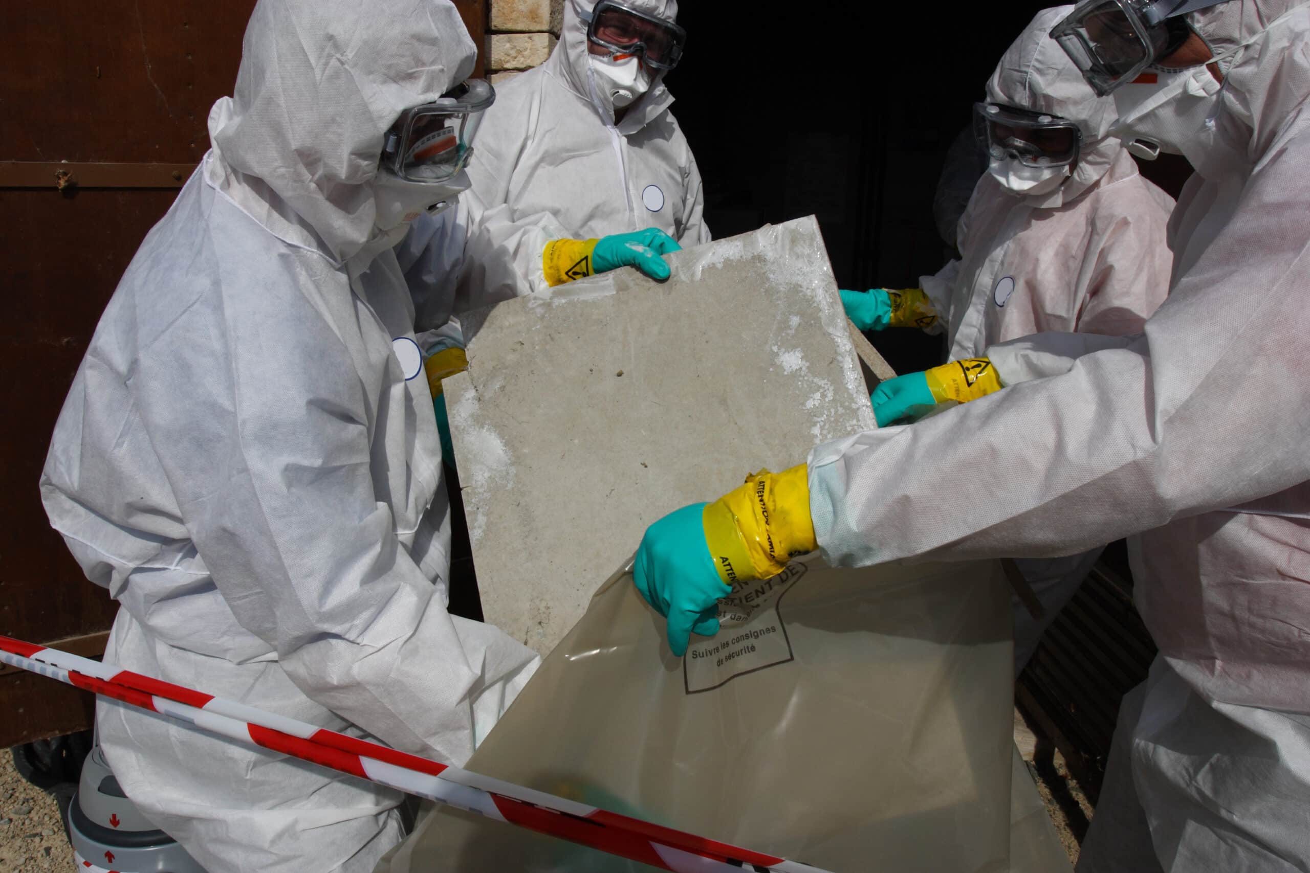 quatre homme en blouse blanche prenant en charge des déchets d'amiante